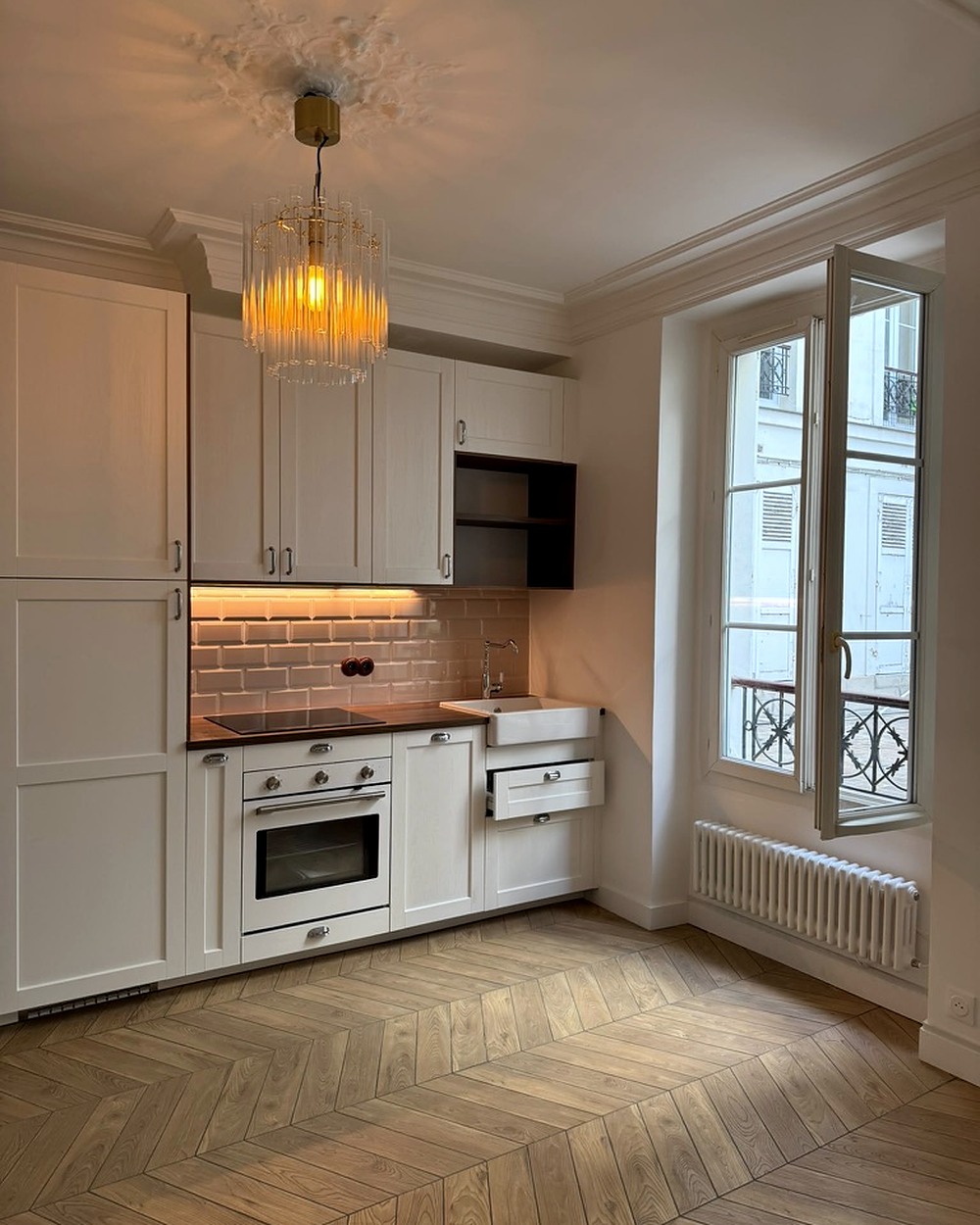 Cuisine équipée dans un appartement haussmannien, parquet chevron et faïence métro