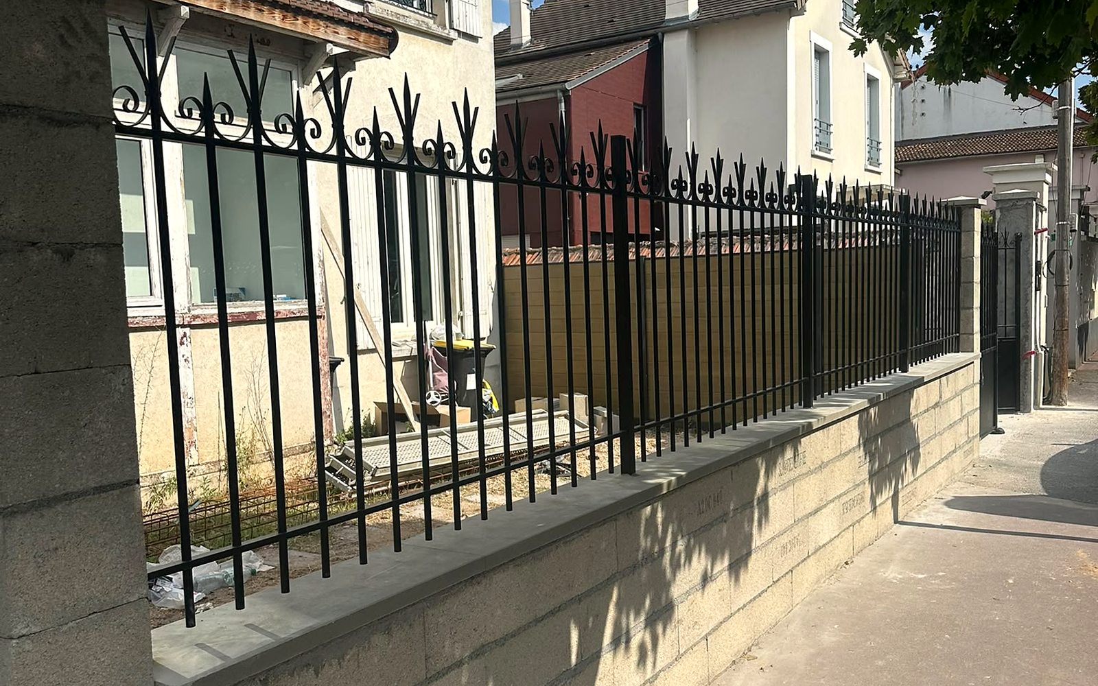 Muret maçonné surmonté d'une grille en fer forgé en limite de propriété